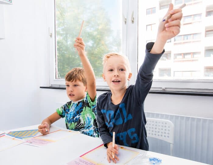Zwei Kinder heben begeistert die Hand während einer Start-Einheit